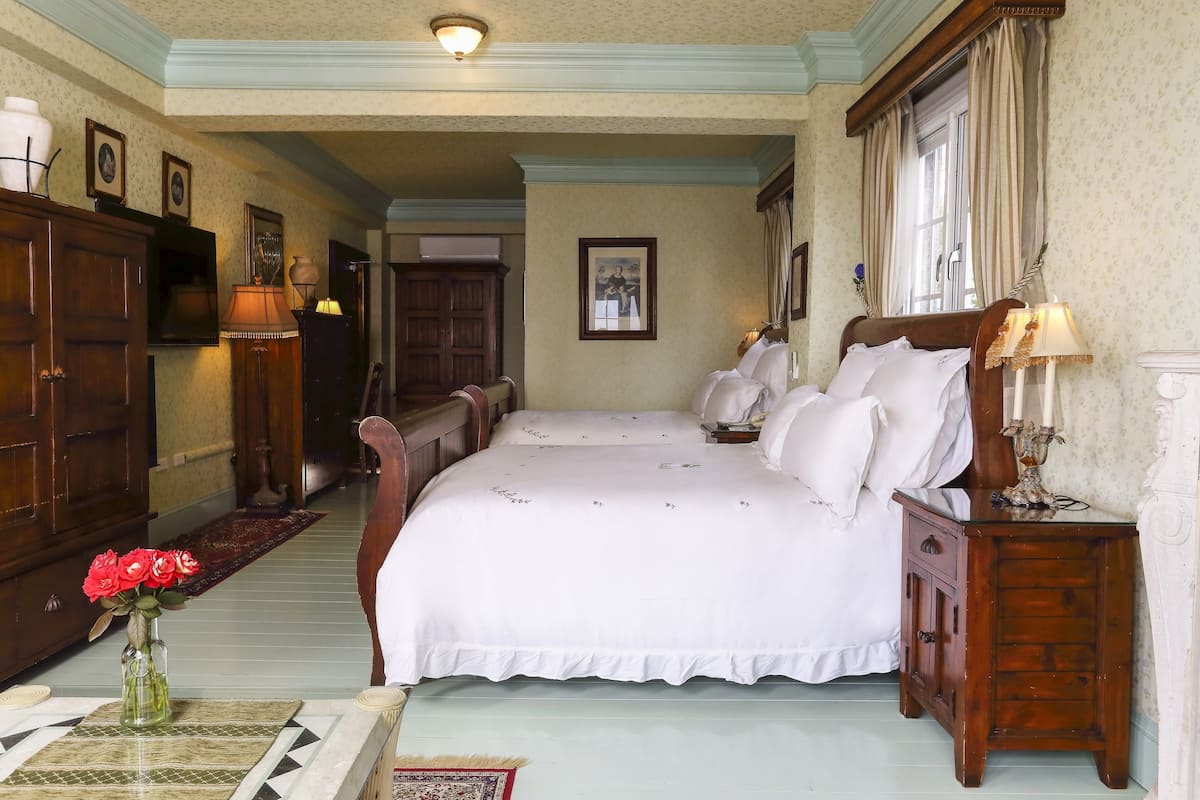 Une chambre à coucher avec un grand lit, des meubles en bois et un vase rempli de fleurs rouges.