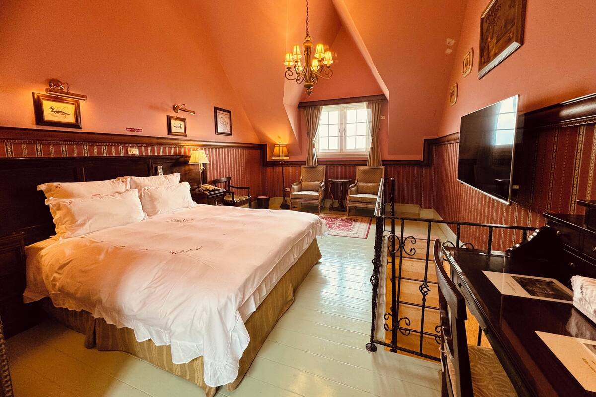 Une chambre spacieuse avec un grand lit, une télévision et un lustre.