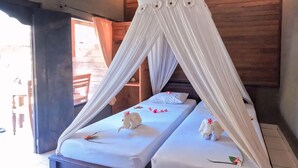 Habitación con dos camas, cada una con dosel y almohadas decorativas.