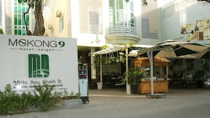 A hotel sign with a green and white logo, outdoor seating area, and a small kiosk.