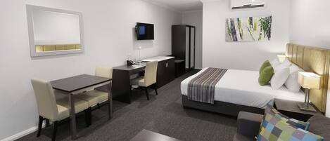 Een moderne hotelkamer met een bed, bureau, stoel en een flatscreen televisie.