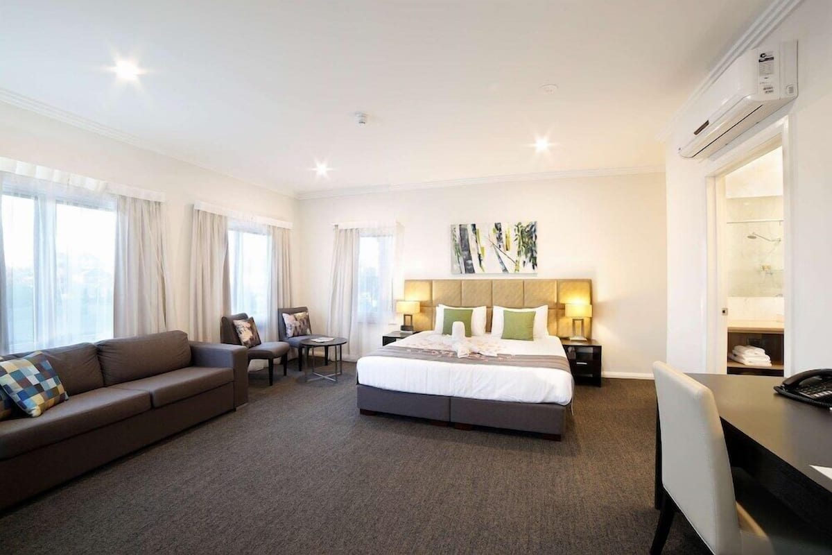 Una habitación de hotel con una cama, un sofá, un escritorio, una silla y una mesita.
