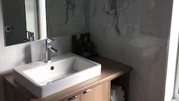 Een badkamer met een witte wastafel, houten opbergmeubel en een grote spiegel.