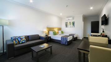 A hotel room with a sofa, a bed, a desk, and a TV.