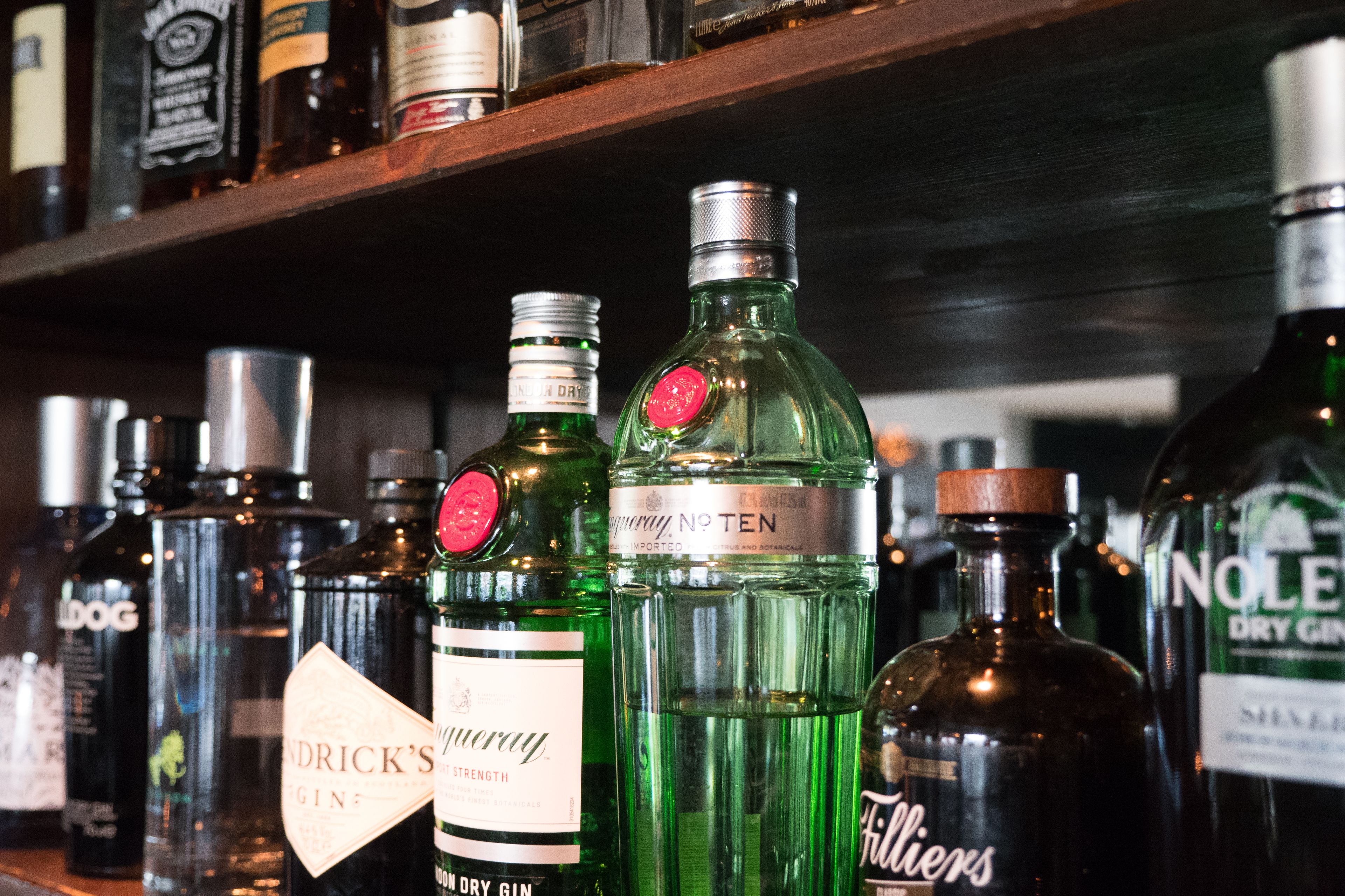 Una estantería con varias botellas de ginebra y otros licores.