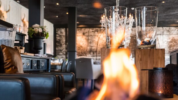 A modern interior with leather seating, a fireplace, and decorative glass vases. - Hotel Café Restaurant Dallinga (Sluiskil)