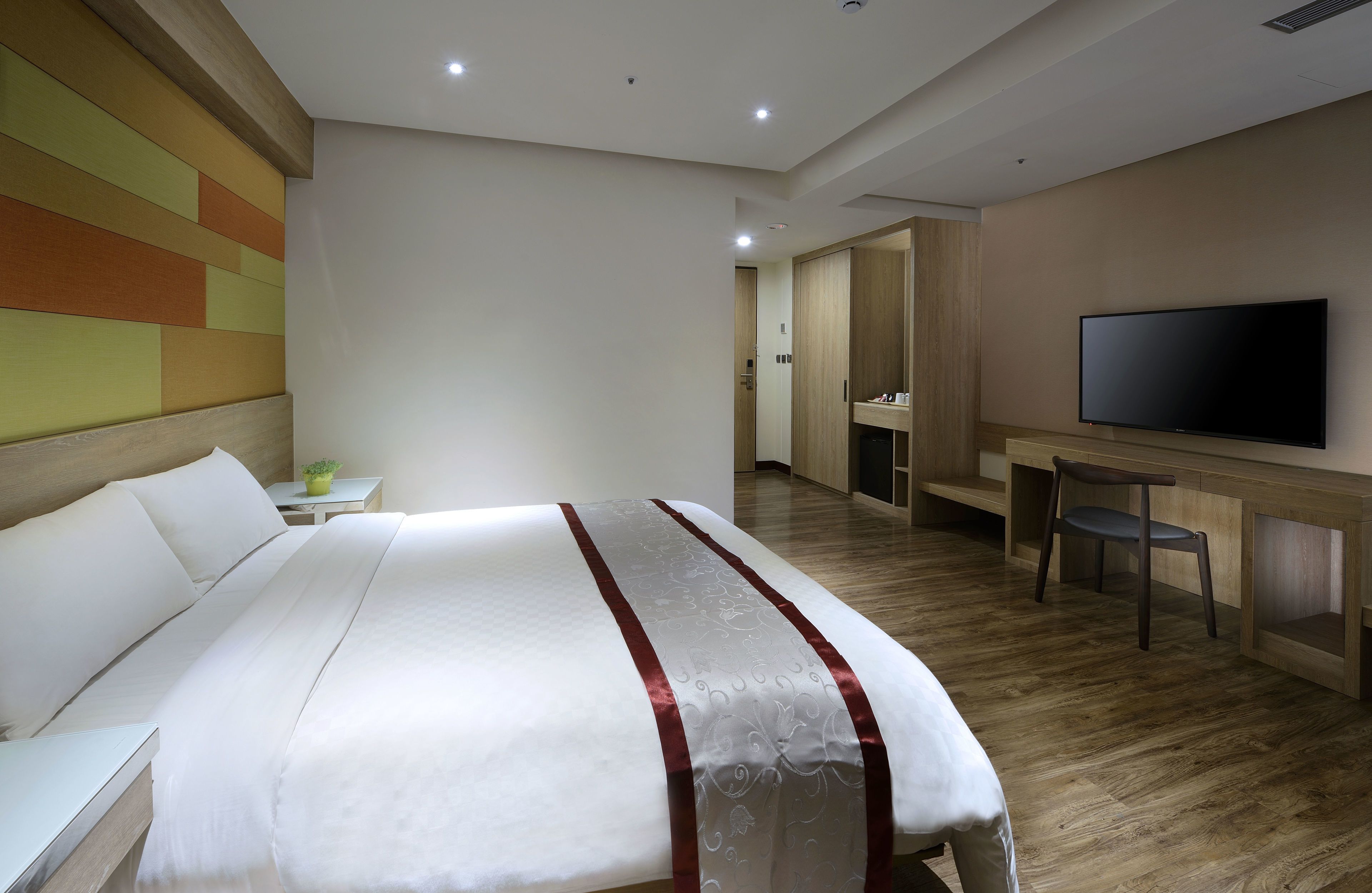 Una habitación de hotel con una cama grande, televisión, escritorio y una silla.