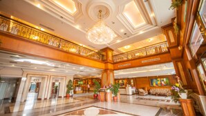 A spacious lobby with a grand chandelier, a reception desk, and a seating area with sofas. - Cheng Pao Hotel (Puli)