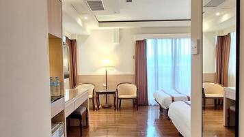A hotel room with a bed, a desk, a chair, a mirror, and a window with curtains.