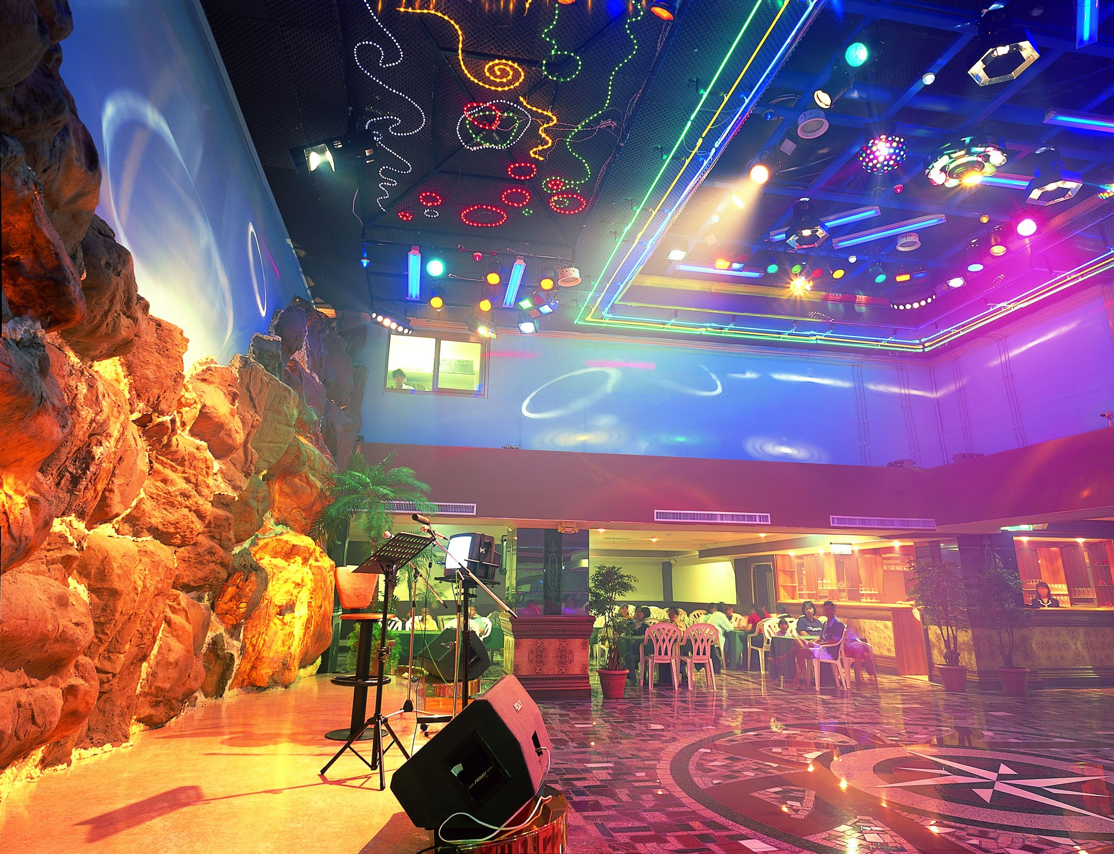 Un hall de hotel con un escenario, asientos y un techo decorativo.