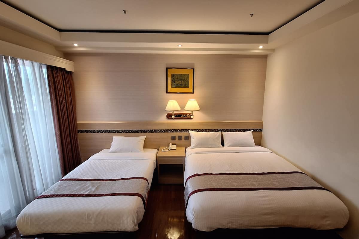 Habitación de hotel con dos camas, una mesita de noche con un teléfono, dos lámparas de pared y un cuadro en la pared.