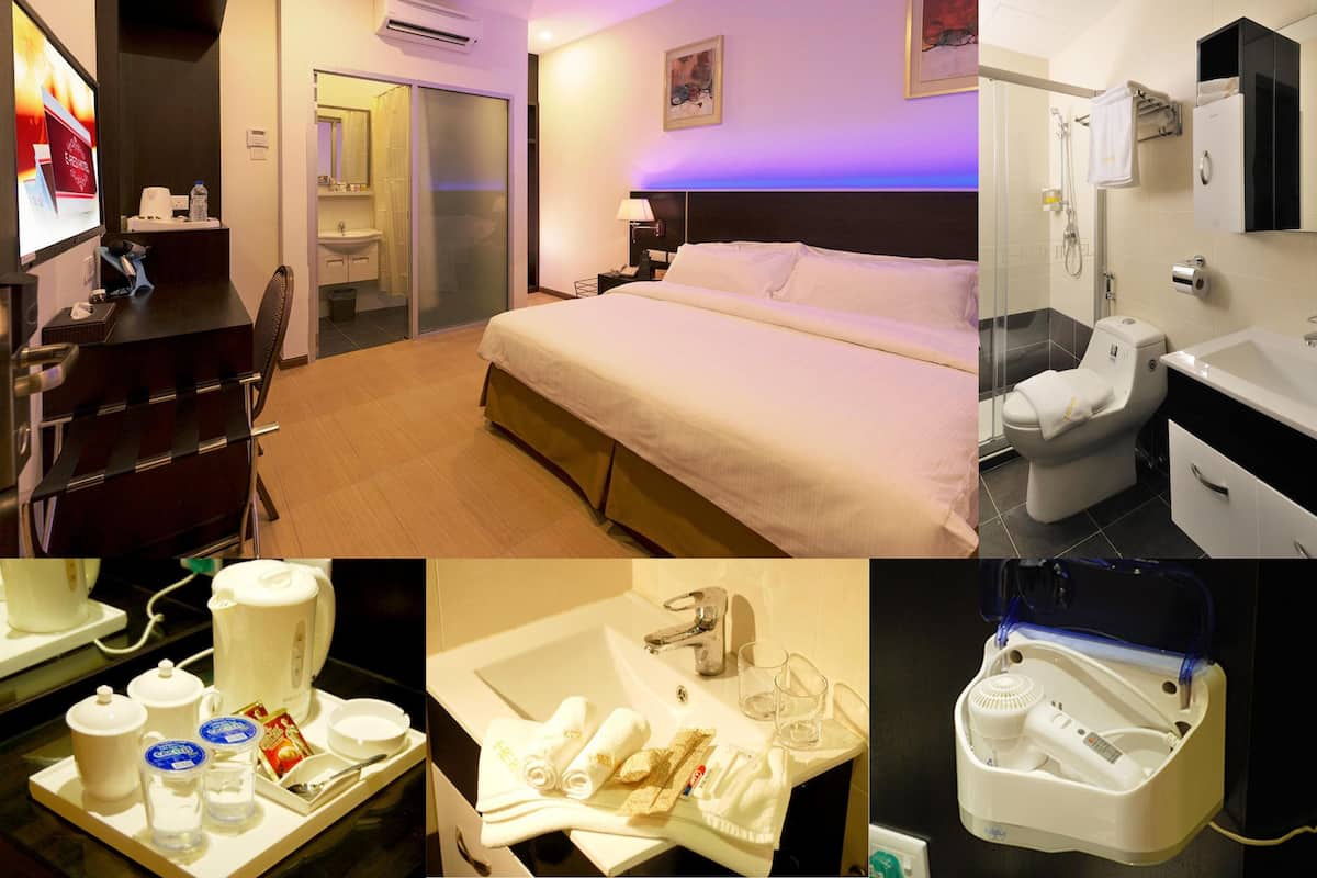 A hotel room with a bed, a desk, a bathroom with a sink and toilet, and a minibar.