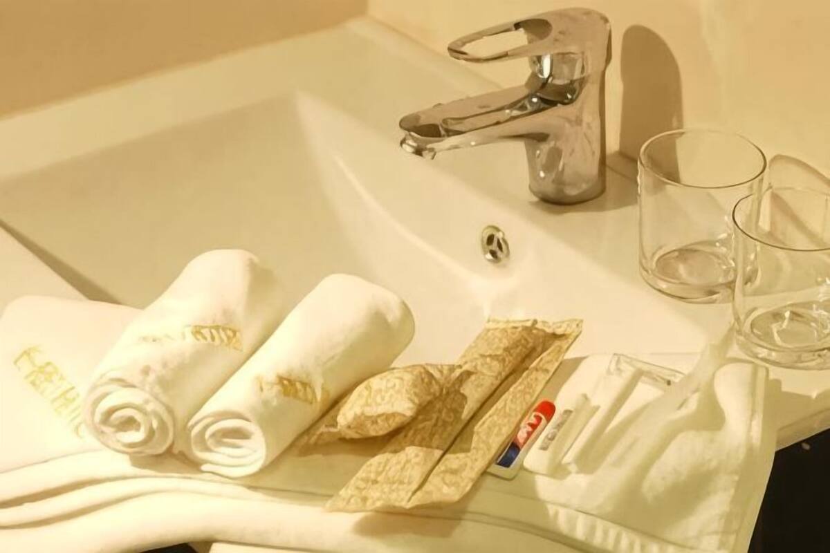 A bathroom sink with towels, a toothbrush, and a glass.