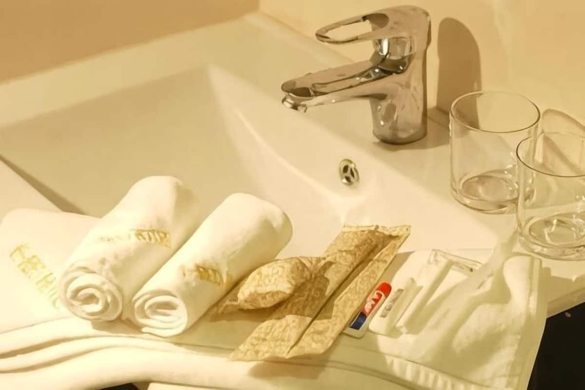 Un lavabo de baño con toallas, un cepillo de dientes y un vaso.