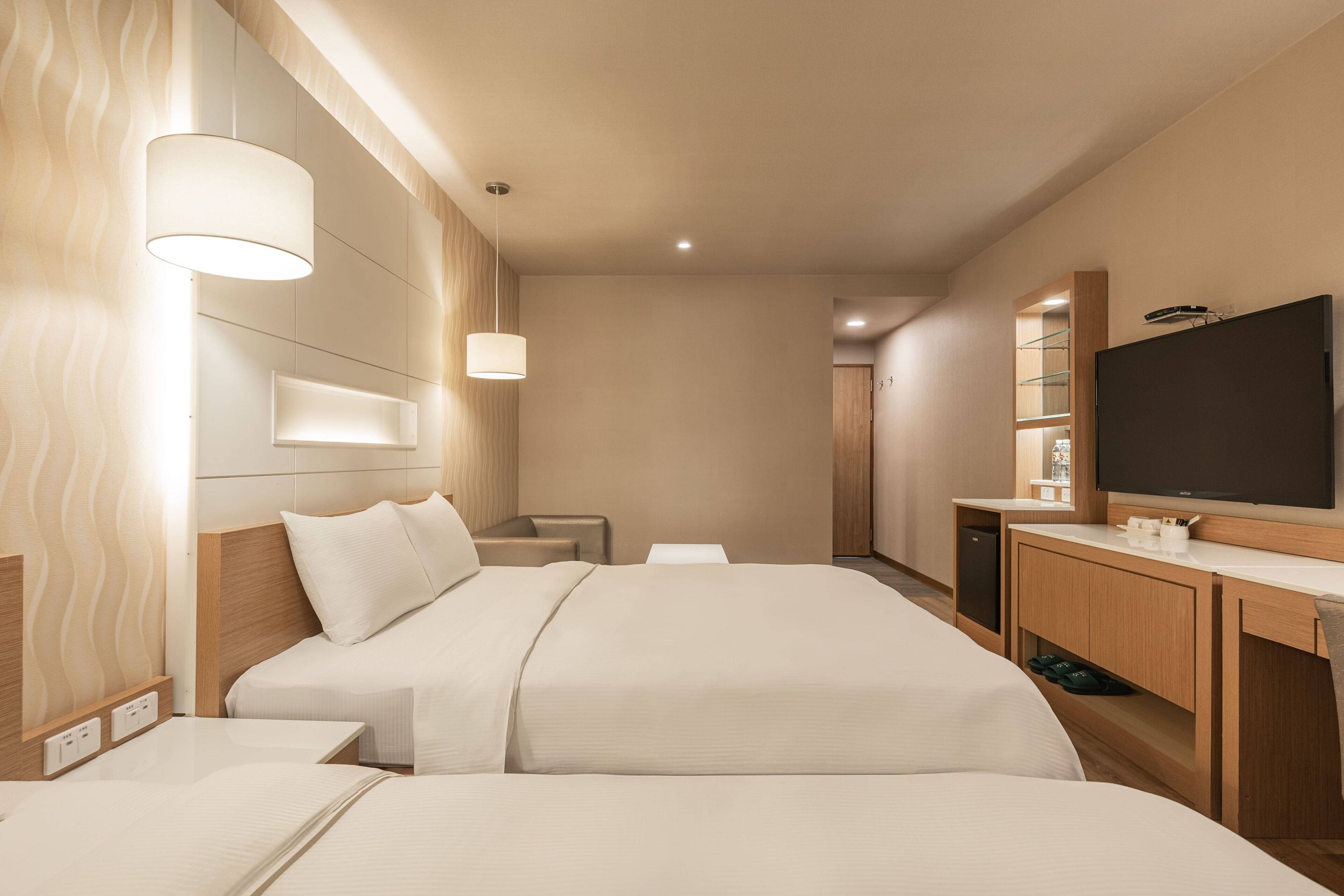 Una habitación de hotel con una cama grande, mesitas de noche, un televisor y un armario de madera.