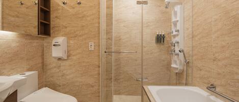 Un baño con inodoro, ducha con mampara de vidrio y bañera.