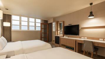 A hotel room with two beds, a desk, a TV, and a wardrobe.