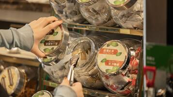 A person selecting tea from a shelf in a store.