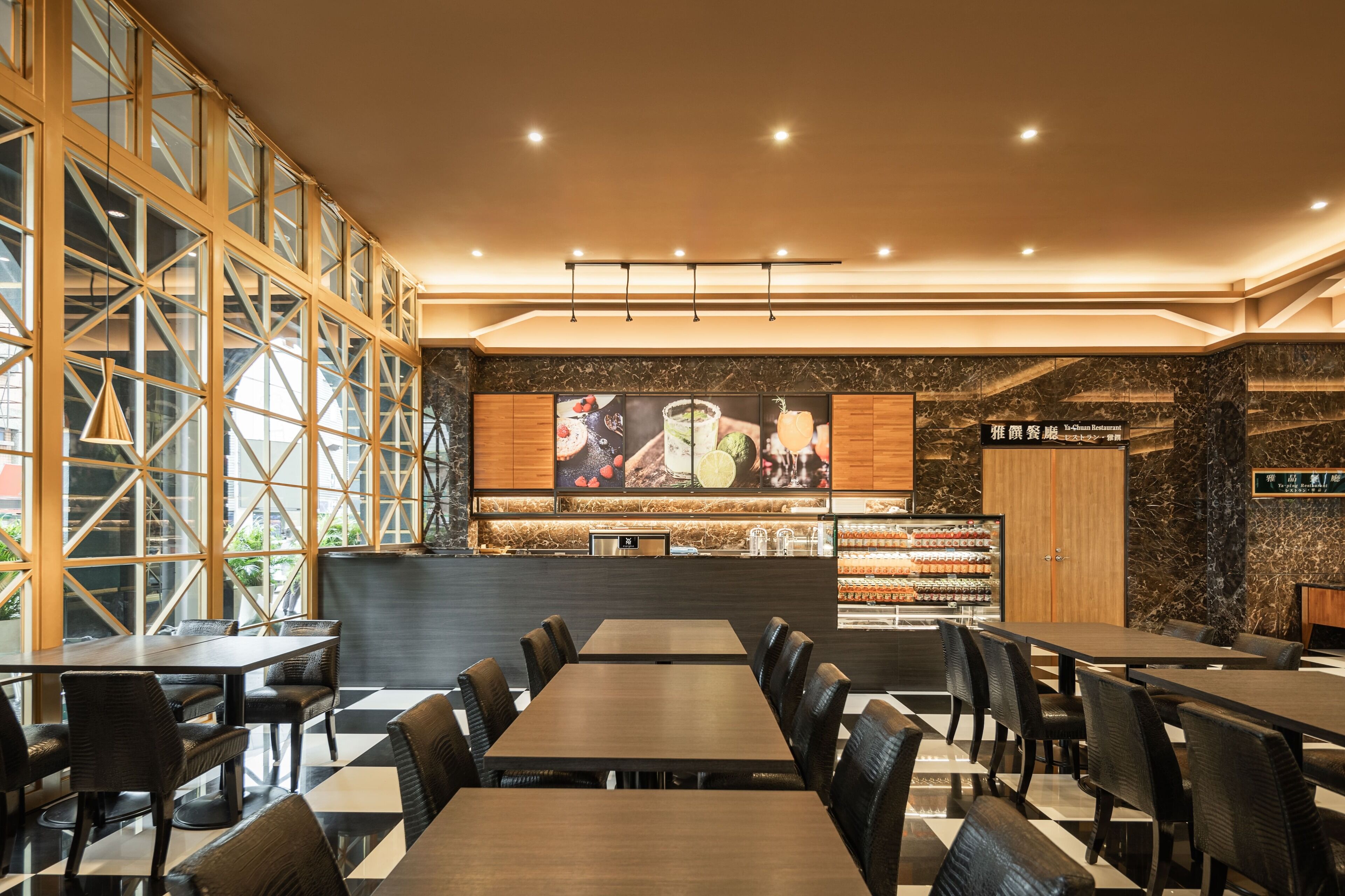 A restaurant with a modern interior, featuring a long counter, multiple seating areas, and a large menu display.