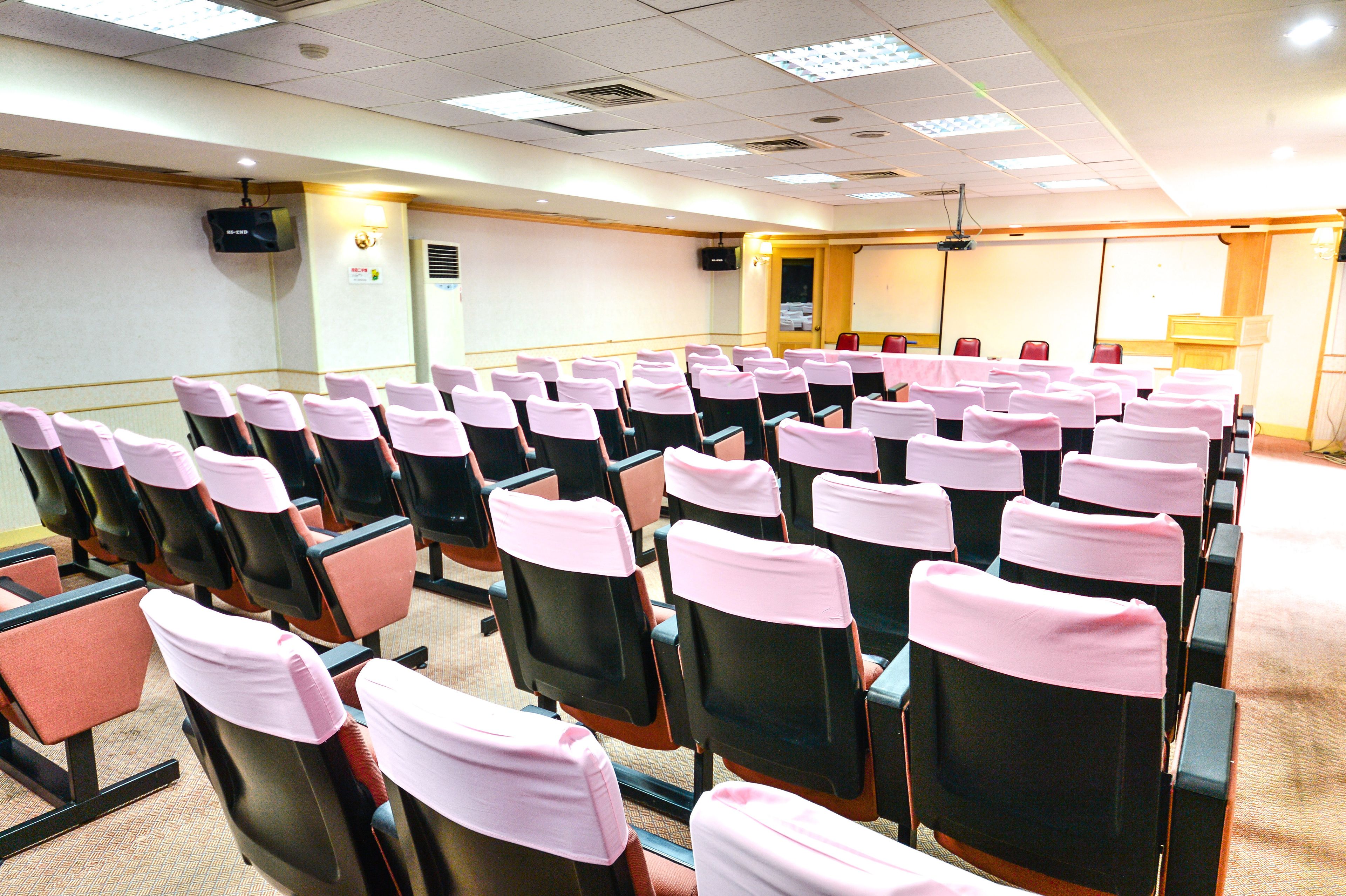 A conference room with rows of chairs, a projector screen, and a podium.