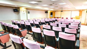 A conference room with rows of chairs, a projector screen, and a podium.