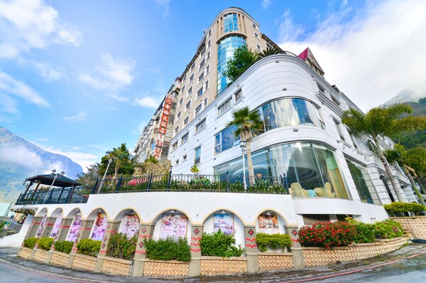 A multi-story hotel with a curved facade, large windows, and a balcony with plants. - Hotel Tilun Dongpu Spa (Xinyi)