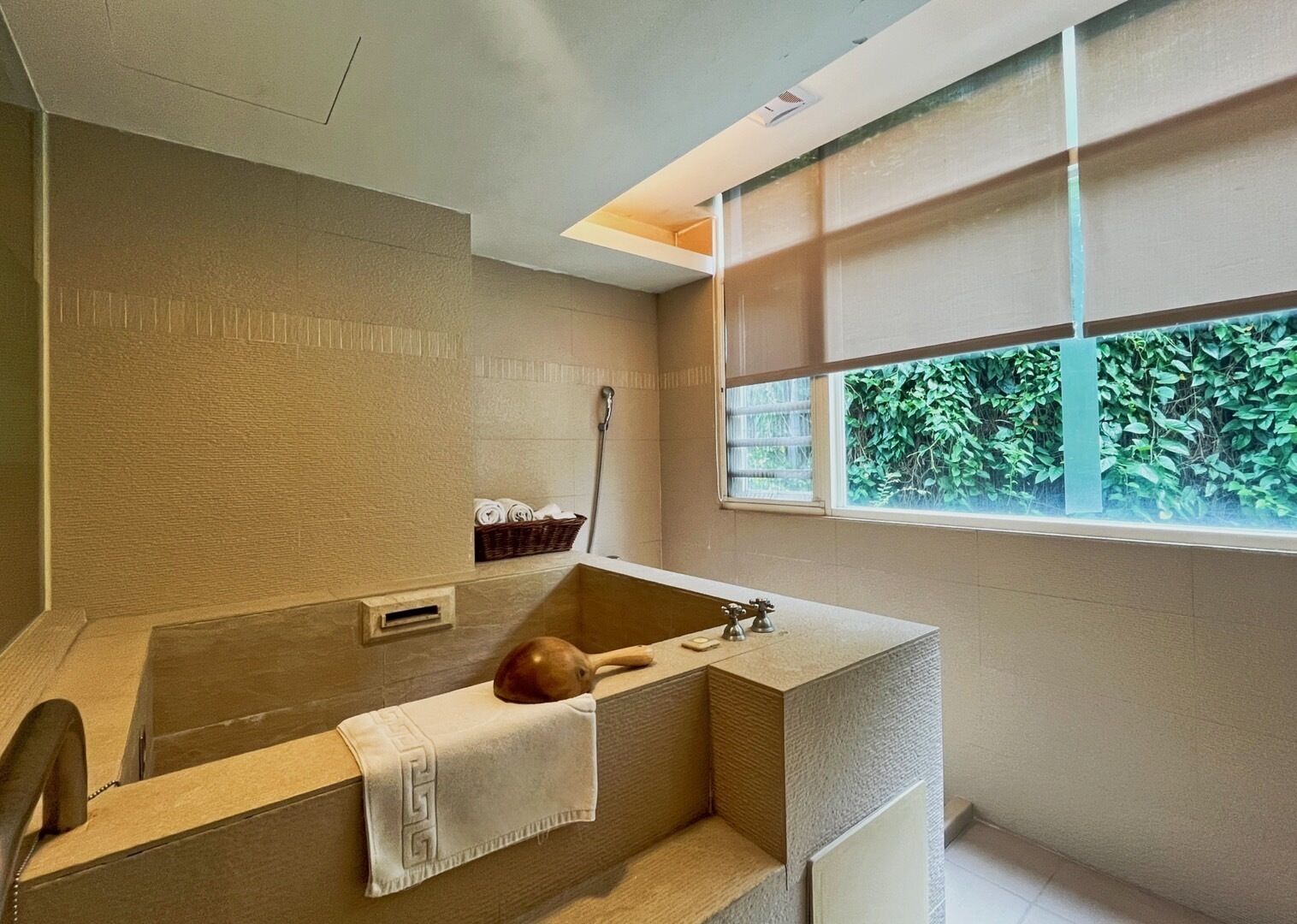 A modern bathroom with a freestanding bathtub, a shower, and a window with a view of greenery.