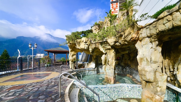 A pool area with a stone pathway, a gazebo, and a mountain backdrop. - Hotel Tilun Dongpu Spa (Xinyi)