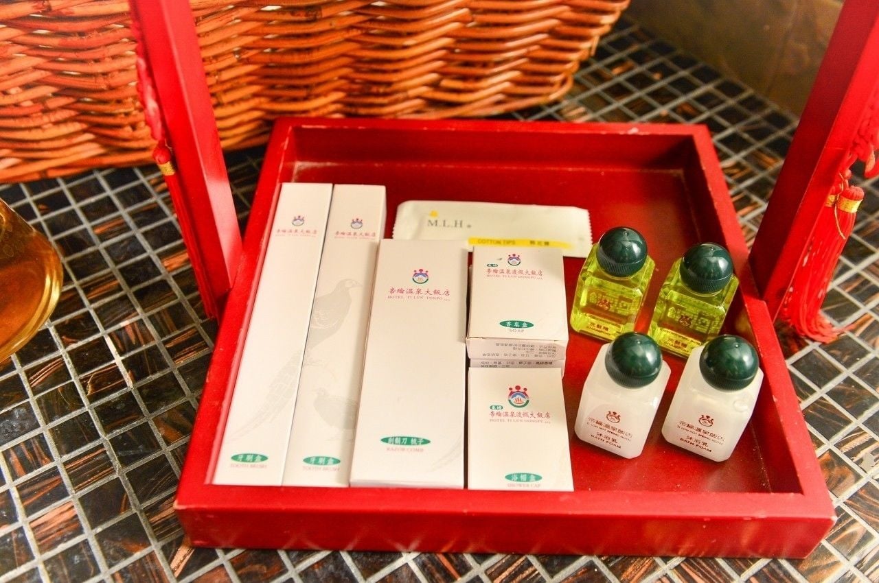 A red tray containing various toiletries including soap bars and bottles.