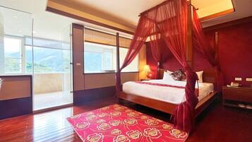 A spacious bedroom with a four-poster bed, a large window, and a view of the outdoors.