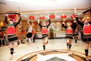 A group of performers in traditional attire dancing in a hotel lobby with a marble floor and red lanterns. - Hotel Tilun Dongpu Spa (Xinyi)