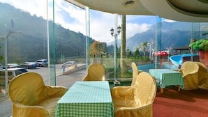 A restaurant with outdoor seating, a pool, and a mountain view. - Hotel Tilun Dongpu Spa (Xinyi)