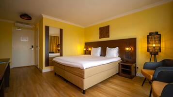 A hotel room with a bed, bedside table, lamp, and a chair.