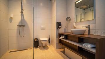 Een moderne badkamer met douche, toilet en wastafel met een wasbak en spiegel.