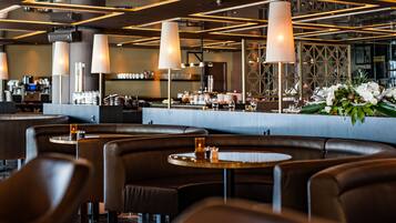 Een modern restaurantinterieur met leren zitbanken, ronde tafels en hanglampen.