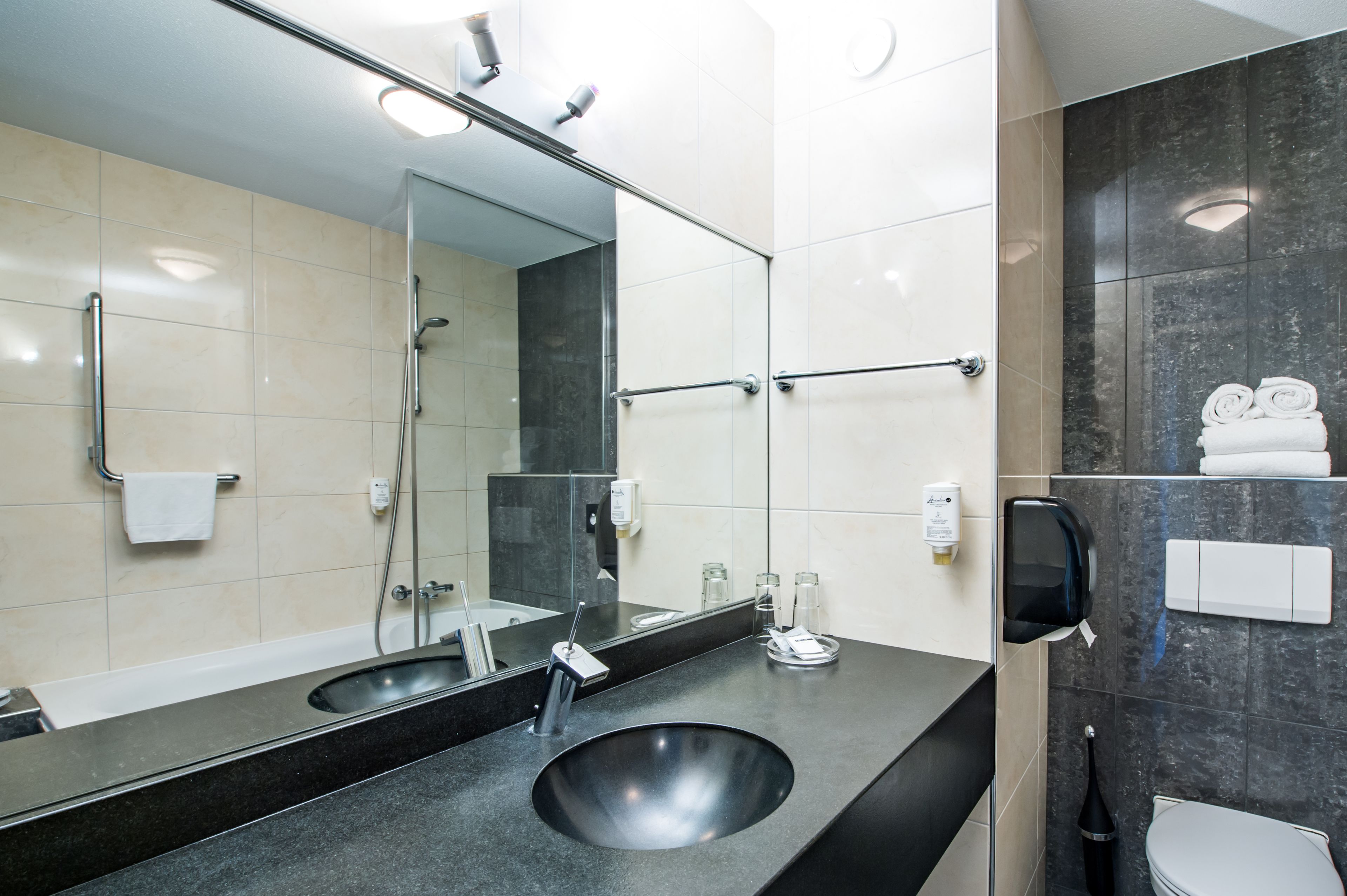 Une salle de bain moderne avec un grand miroir, deux lavabos, une douche et des toilettes.