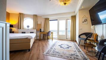 Una habitación de hotel con cama, escritorio, silla y un ventanal grande.