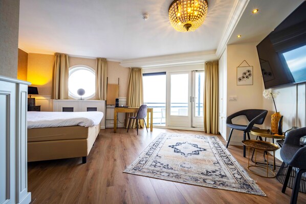 Una habitación de hotel con cama, escritorio, silla y un ventanal grande.