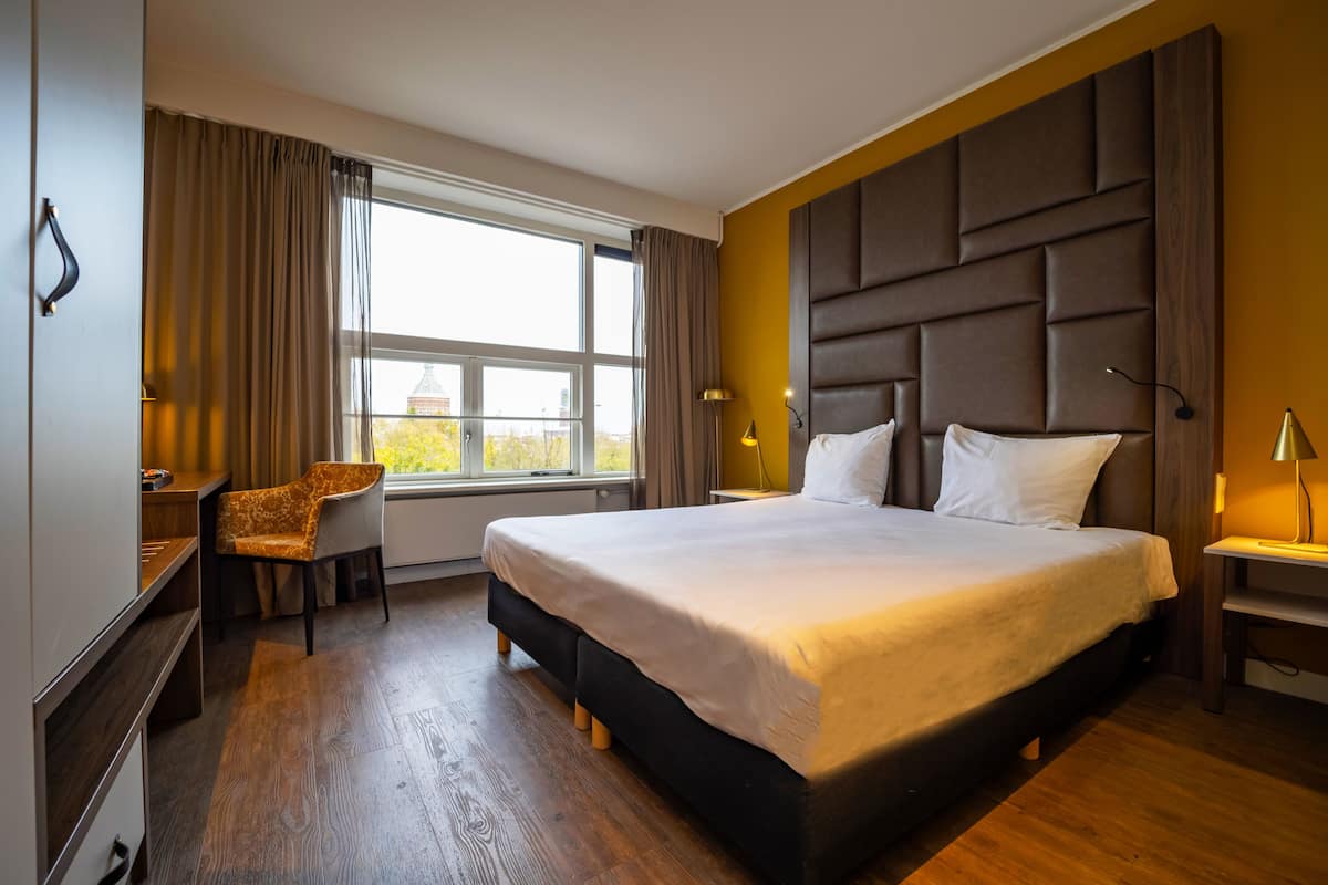 Una habitación de hotel moderna con una cama grande, un escritorio y una silla.
