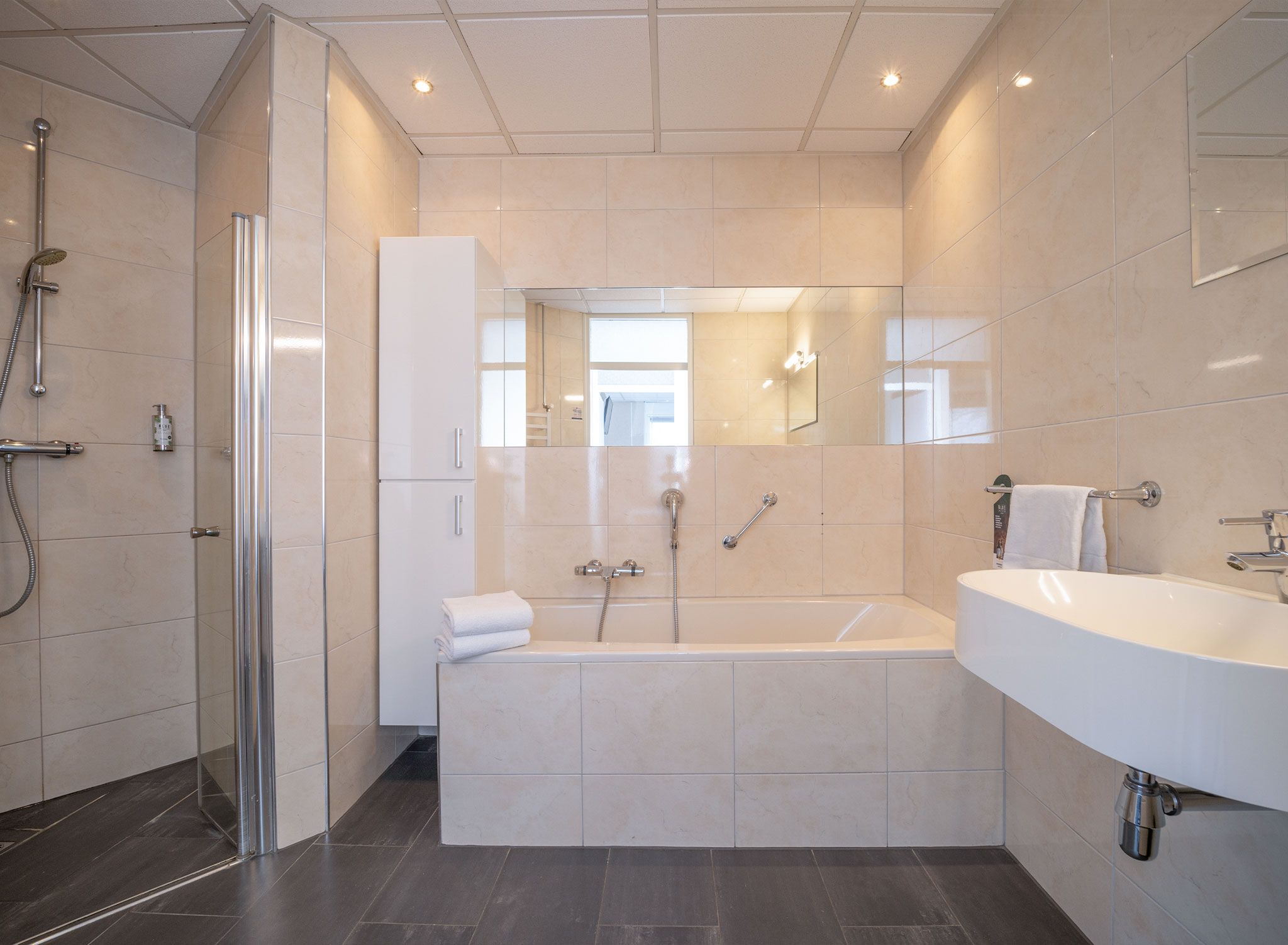 Ein modernes Badezimmer mit bodenebener Dusche, freistehender Badewanne und einem großzügigen Waschtisch.