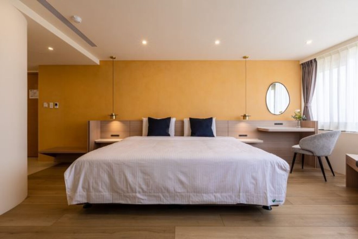 Habitació d'hotel moderna amb un llit gran, taules de nit, escriptori i una cadira.