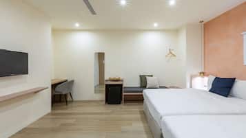 Una habitación de hotel moderna con una cama grande, un escritorio, un refrigerador pequeño y un televisor montado en la pared.