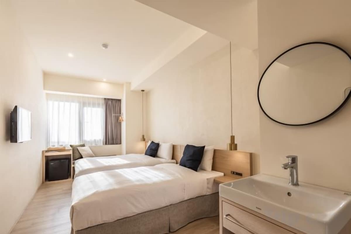Una camera d'albergo con un letto, un comodino e uno specchio grande.