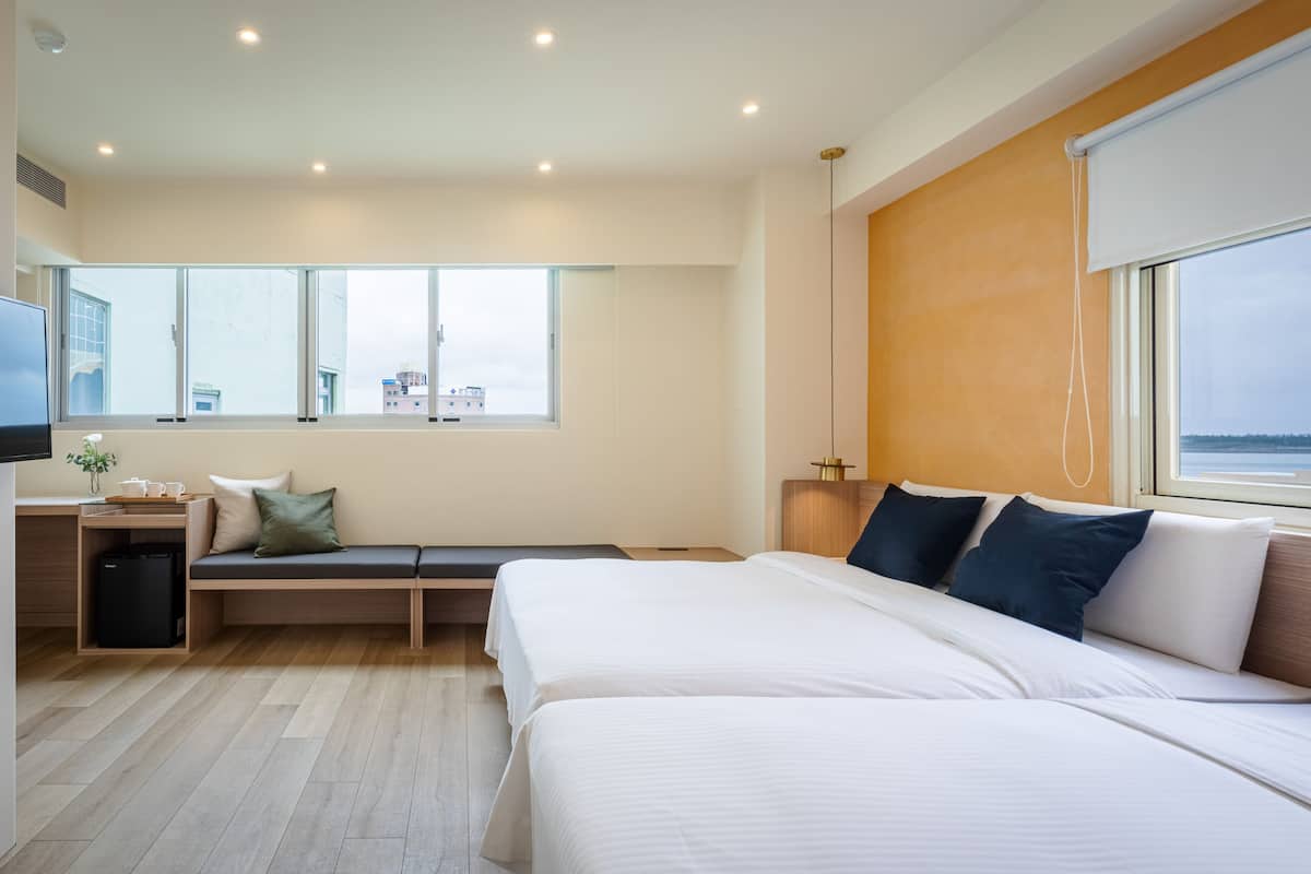 A modern hotel room with a large bed, a seating area, a desk, and a television.