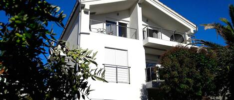 A modern white building with balconies, large windows, and a flat roof.