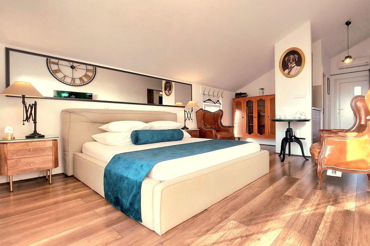 Un dormitorio con una cama, mesitas de noche, una silla, un armario y un reloj de pared.