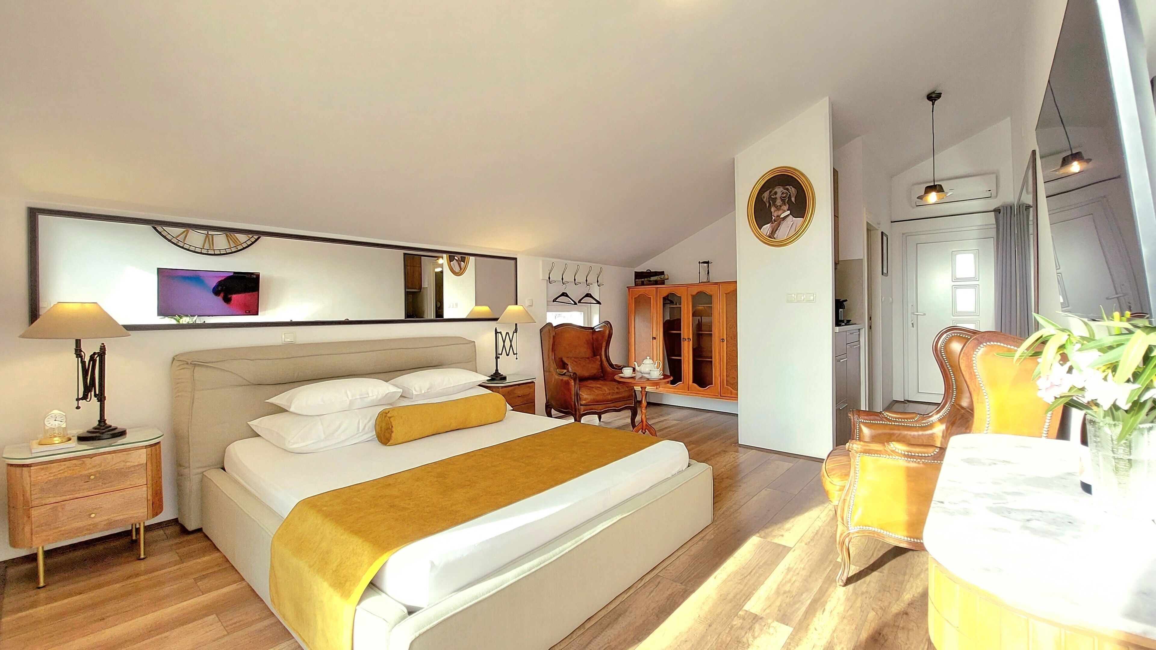 Une chambre d’hôtel moderne dotée d’un grand lit, d’un coin salon avec un fauteuil et une table, d’une armoire et d’un téléviseur.