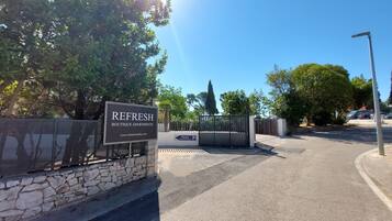 Una entrada protegida por un muro de piedra a Refresh Boutique Apartments, con un cartel.
