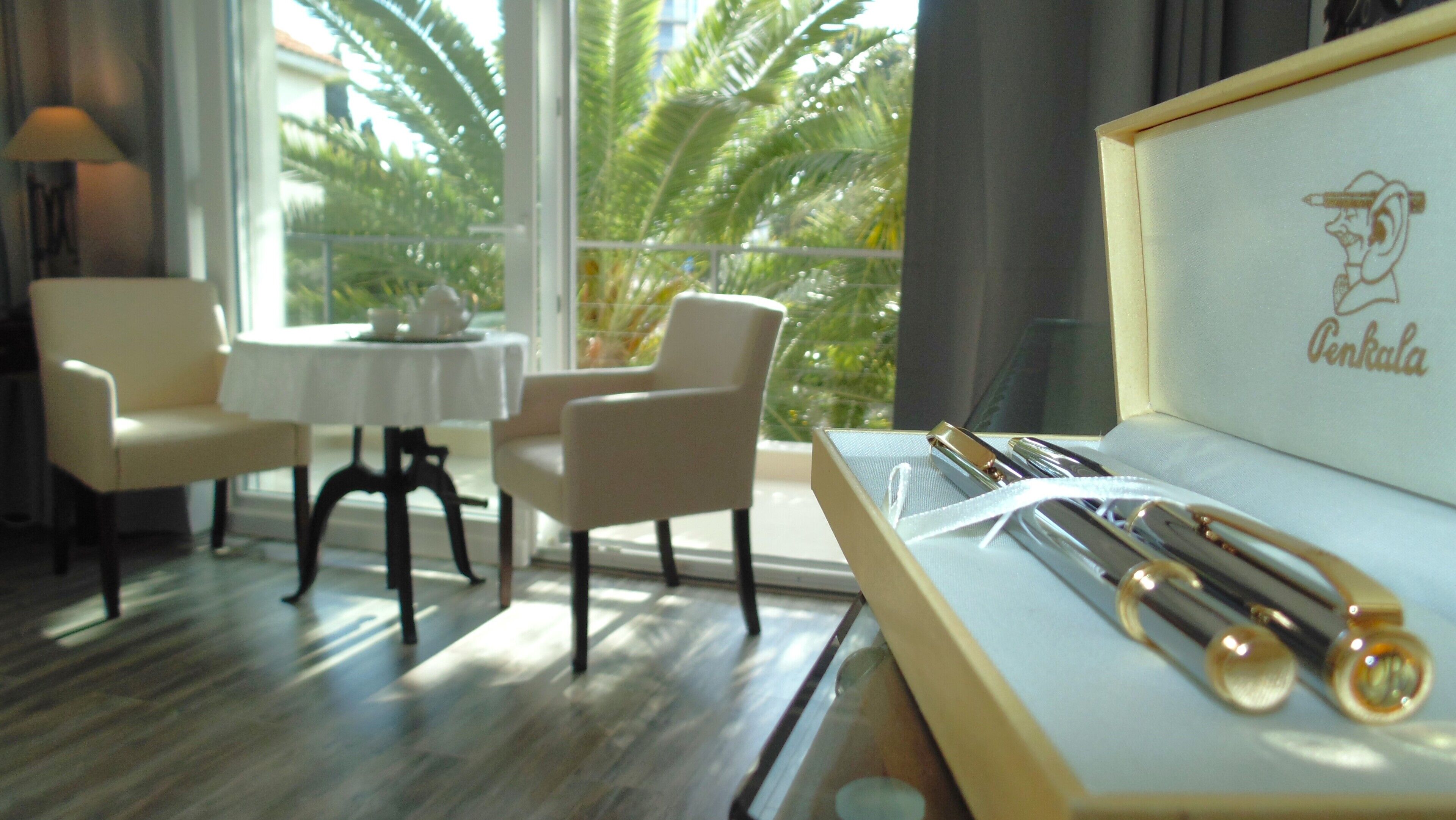 A hotel room with a dining area, a table with chairs, and a framed item on the table.