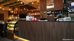 Een moderne hotel receptiebalie met een houten toonbank, een digitaal scherm en een gekoelde drankvitrine.